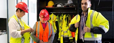 Three employees putting on PPE gear